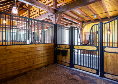interior of horse stall with hay on the floor and light fixture hanging from ceiling